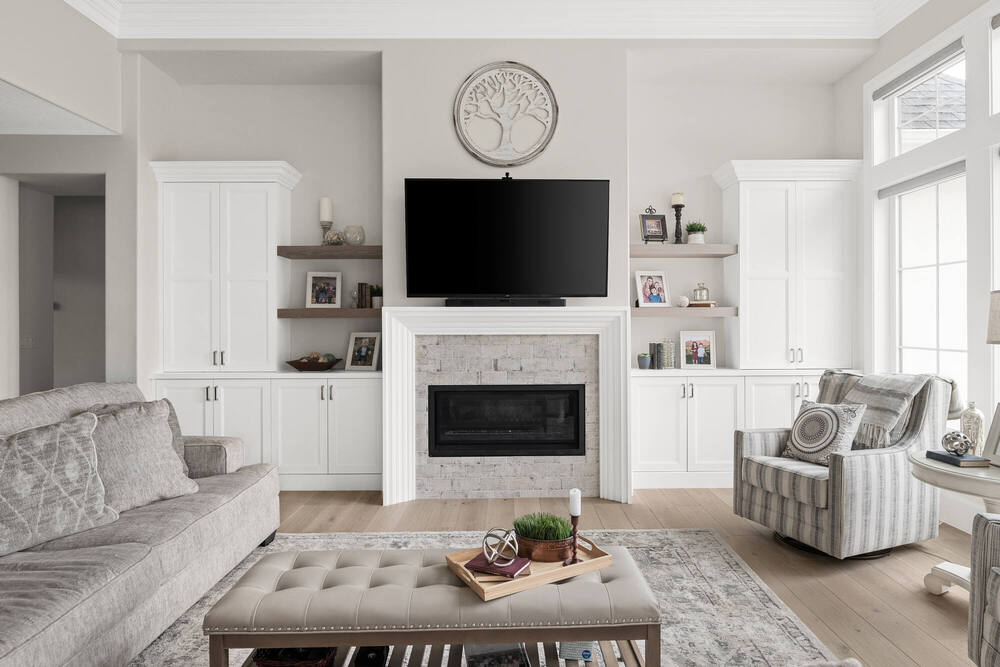 Cozy living room with TV over white fireplace and built-in shelves in custom home by Conner Construction in Pleasant Grove