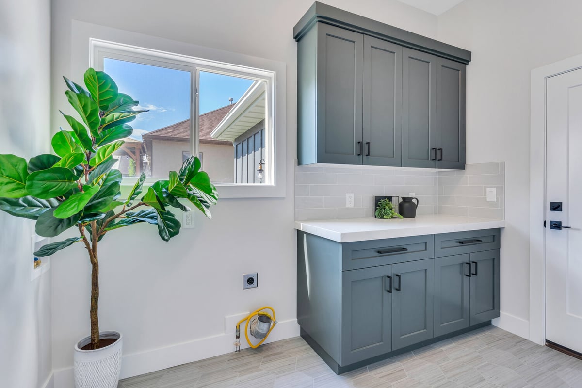 Bright laundry room with dark cabinetry and large window in custom home by Conner Construction Company in Orem, UT