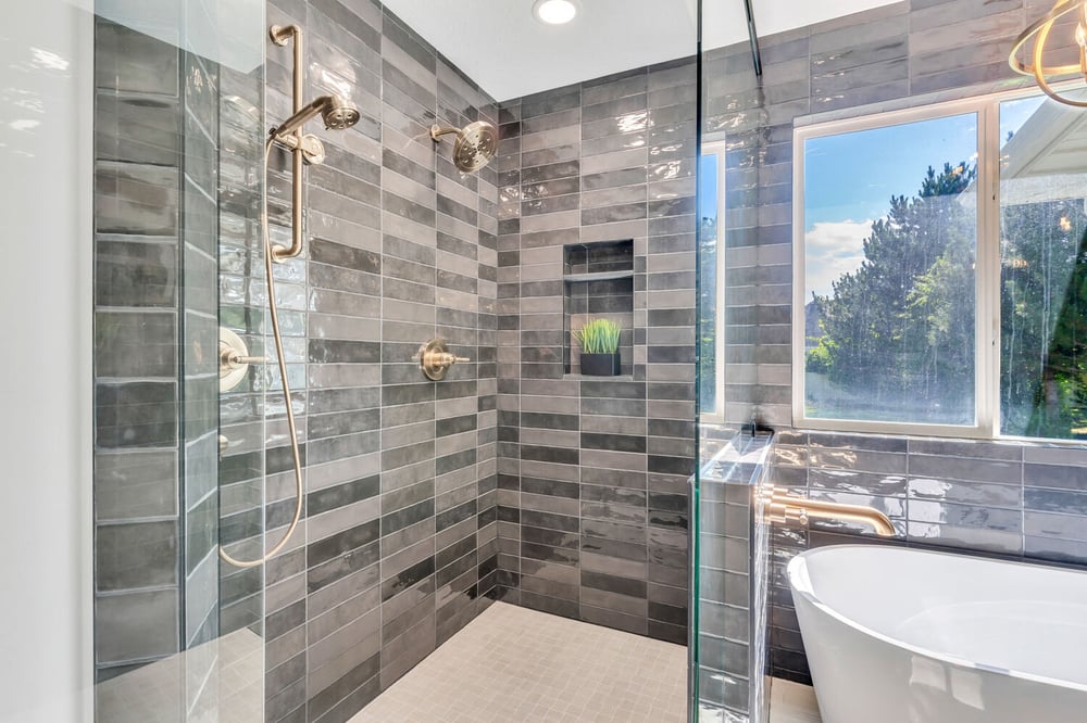 Modern tiled shower with gold fixtures and inset shelf in a custom home by Conner Construction Company in Park City, UT