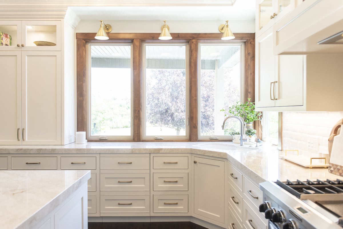 Bright kitchen corner with wood-trimmed windows and marble counters by Conner Construction Company in Lehi, UT