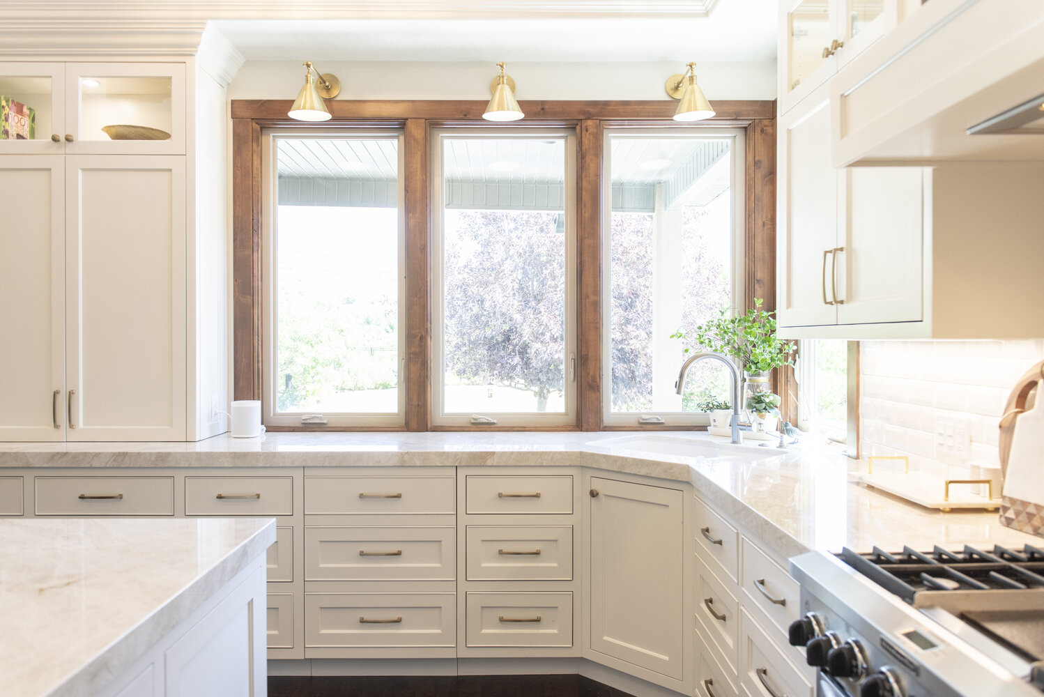 Bright kitchen corner with wood-trimmed windows and marble counters by Conner Construction Company in Lehi, UT