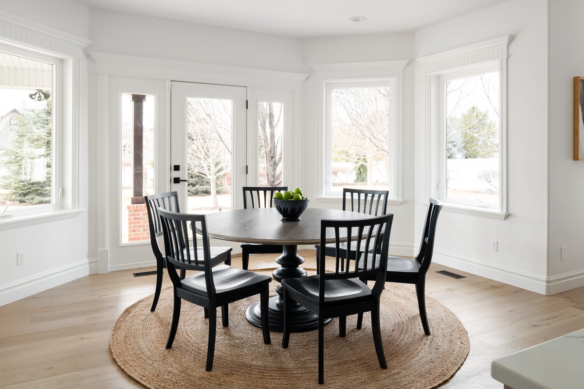 Bright dining nook with round table and large windows in Highland, UT home by Conner Construction Company
