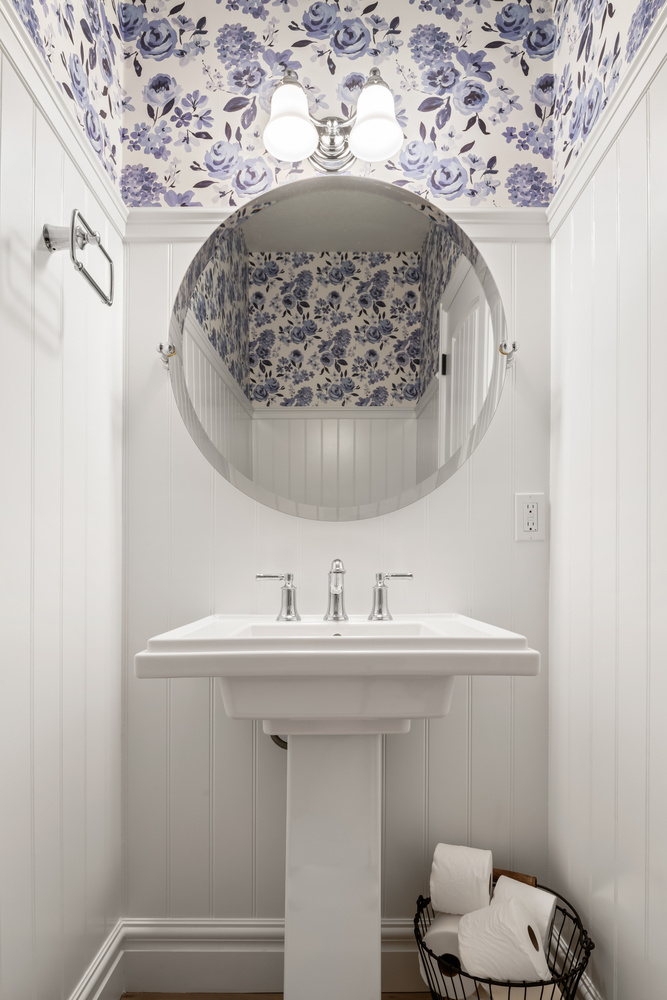 Powder room with floral wallpaper and pedestal sink by Conner Construction Company in Highland, UT