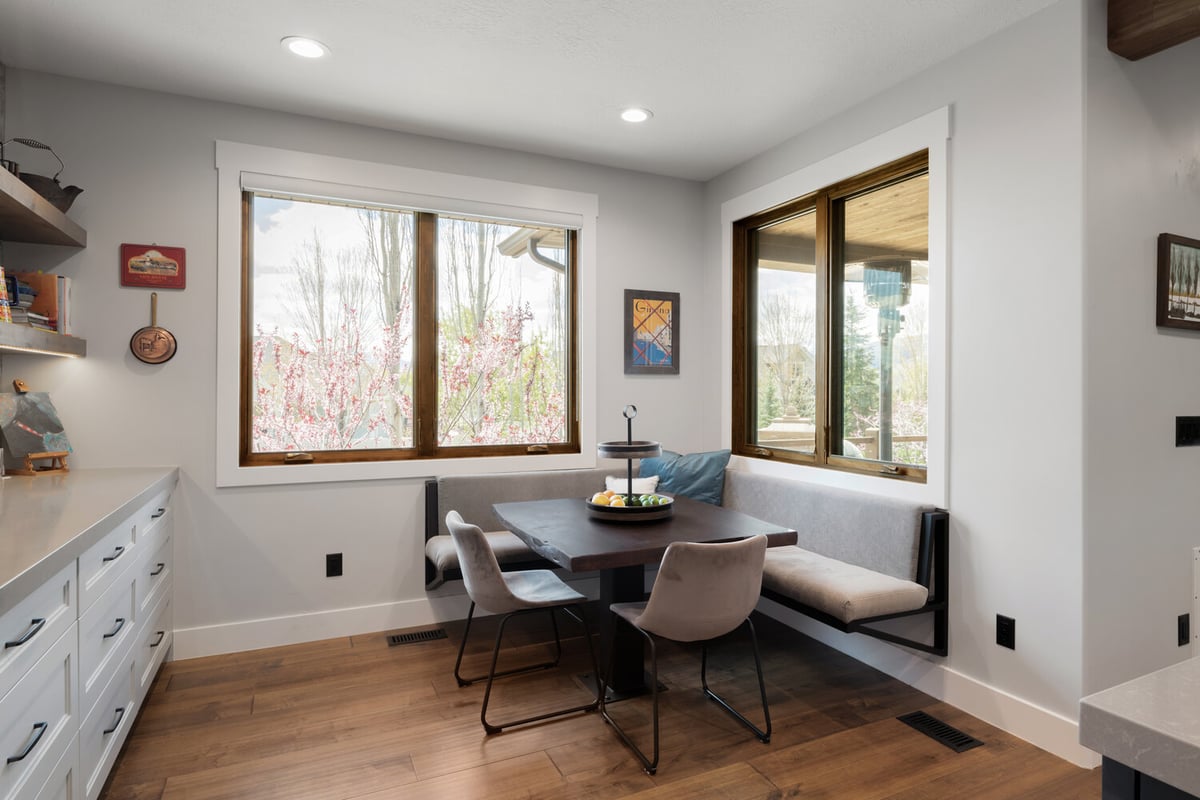Cozy dining corner with large windows and upholstered bench seating by Conner Construction Company in Utah County