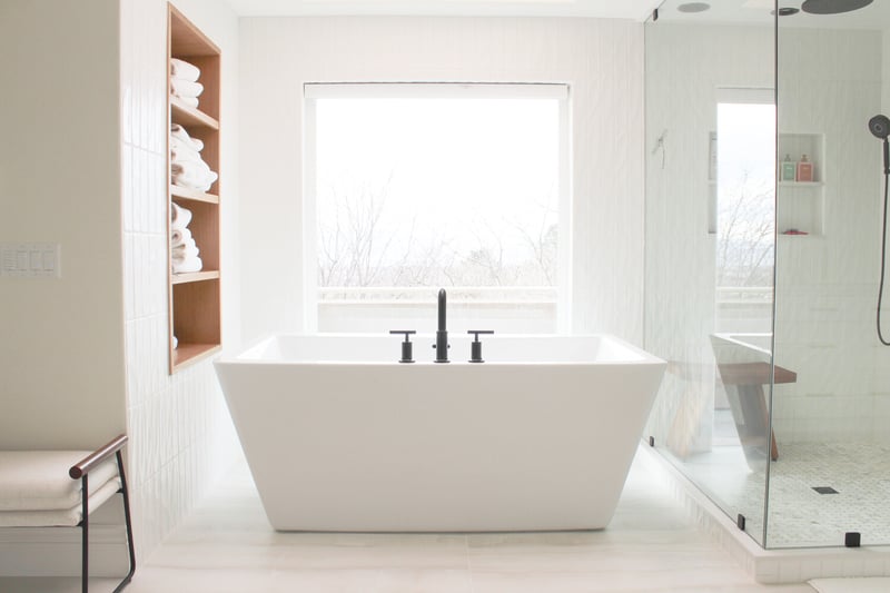 Bright spa-like bathroom with modern bathtub and built-in towel shelving in a Conner Construction custom home in Draper, UT