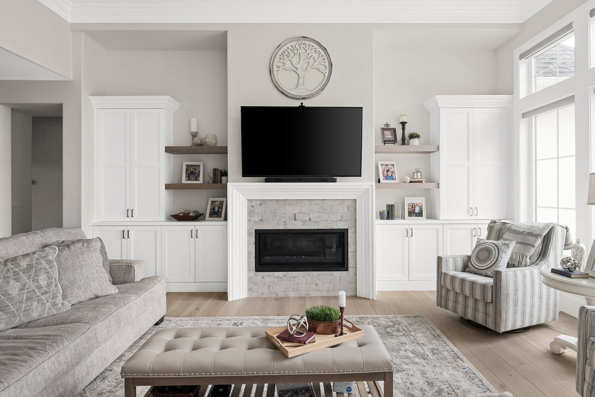 Cozy living room with TV over white fireplace and built-in shelves in custom home by Conner Construction in Pleasant Grove