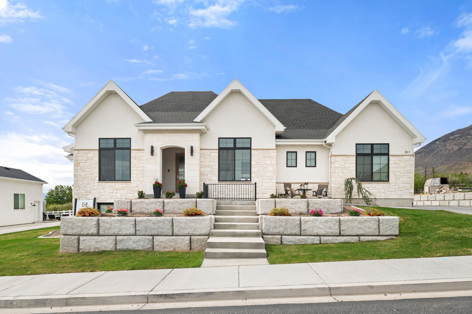 Front elevation of white stone custom home with tiered landscaping in Pleasant Grove, UT by Conner Construction Company