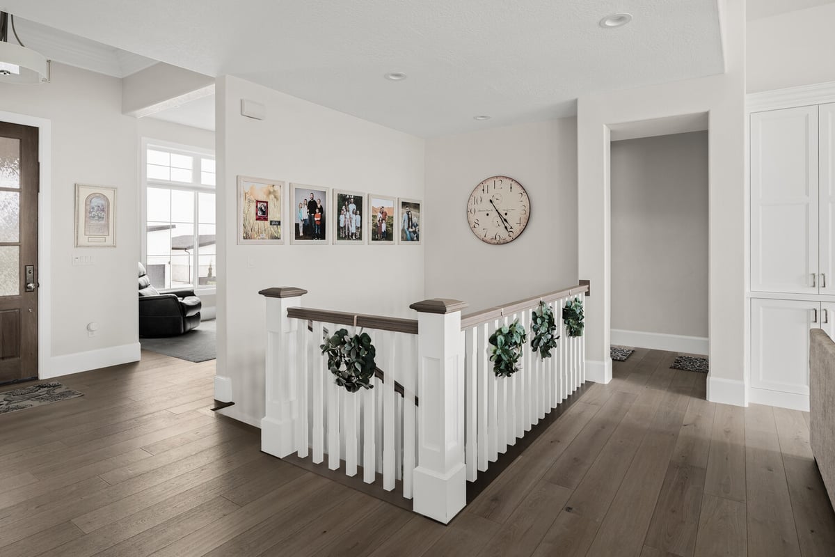 Upstairs hallway with family photo gallery and large wall clock in custom home by Conner Construction in Pleasant Grove, UT