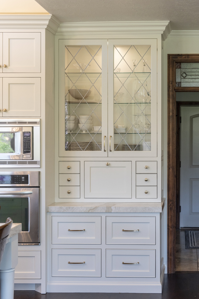 White glass-front cabinetry showcasing dishware in a custom home by Conner Construction Company in Alpine, UT