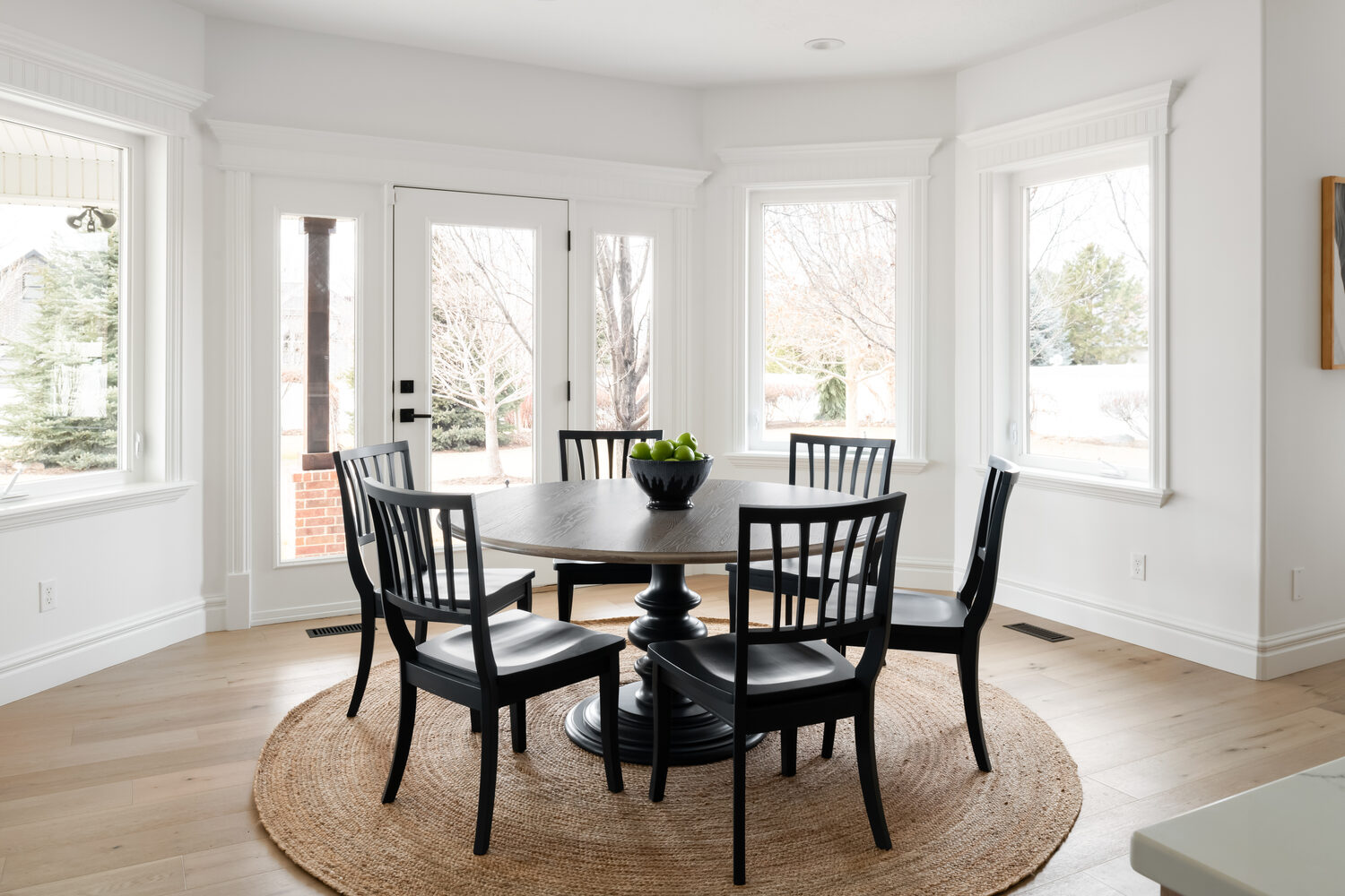 Bright dining nook with round table and large windows in Highland, UT home by Conner Construction Company