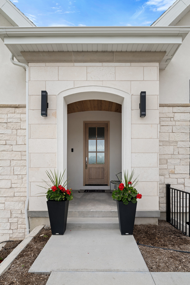 Covered front entryway with arched stone opening in Pleasant Grove custom home by Conner Construction Company