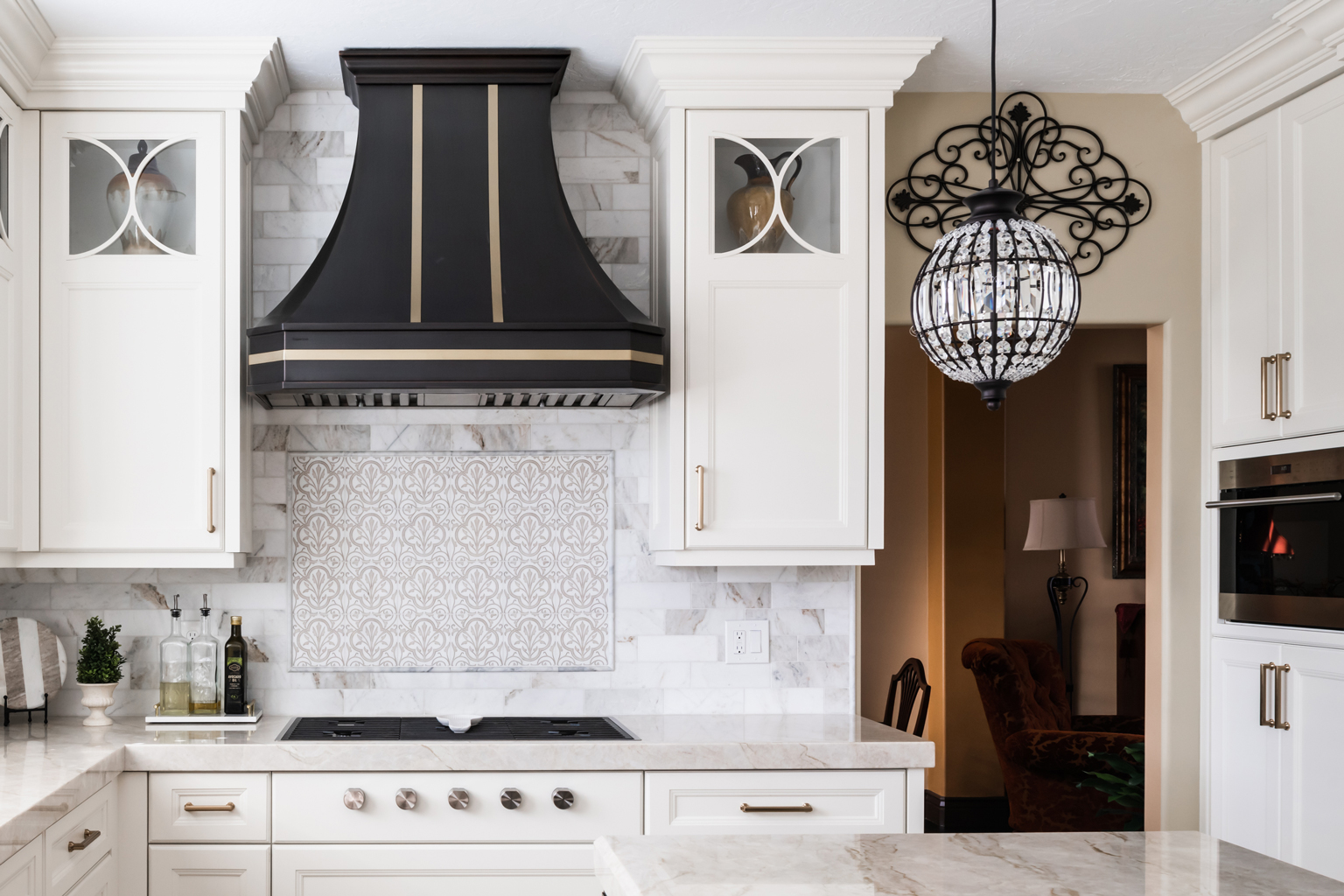 Utah Custom Home Builders' elegant kitchen with white theme, black hood, marble counter.