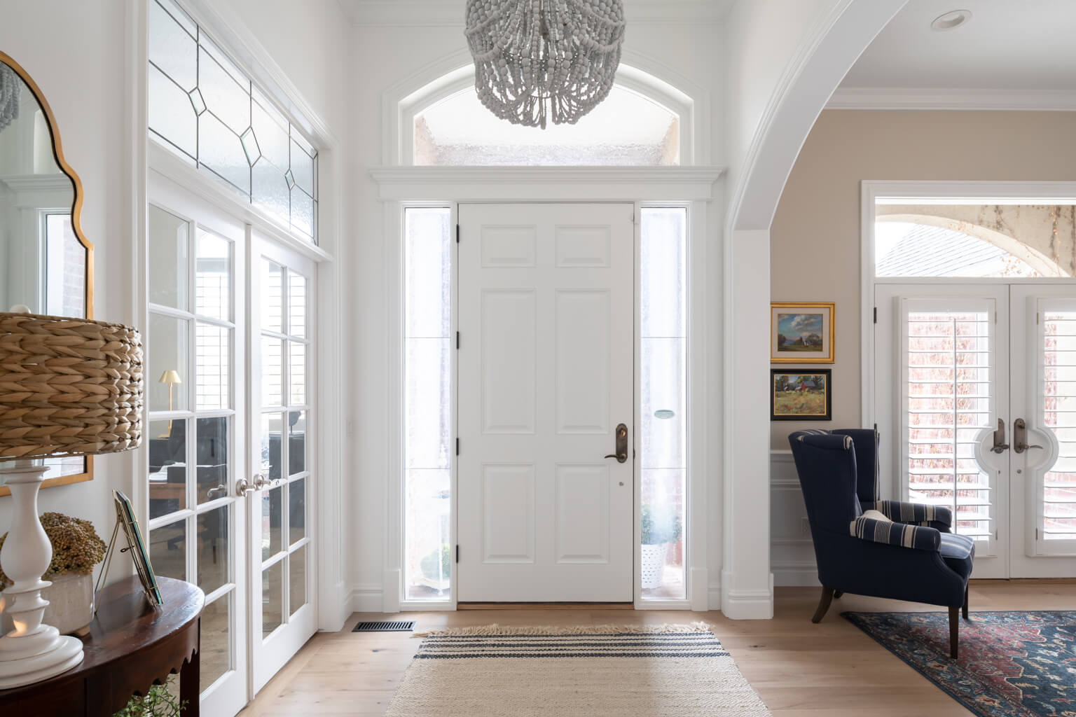 A luxurious foyer with an elegant chandelier and a stylish rug, showcasing the craftsmanship of Utah Home Builders.