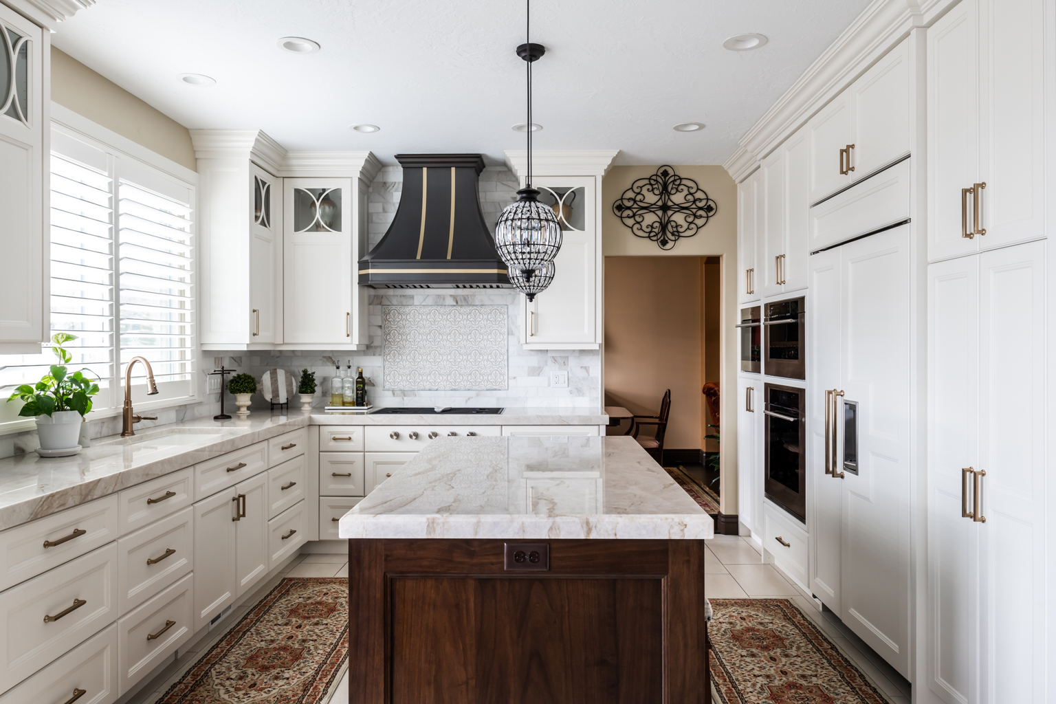 Utah Custom Home Builders' kitchen featuring white cabinets and marble island