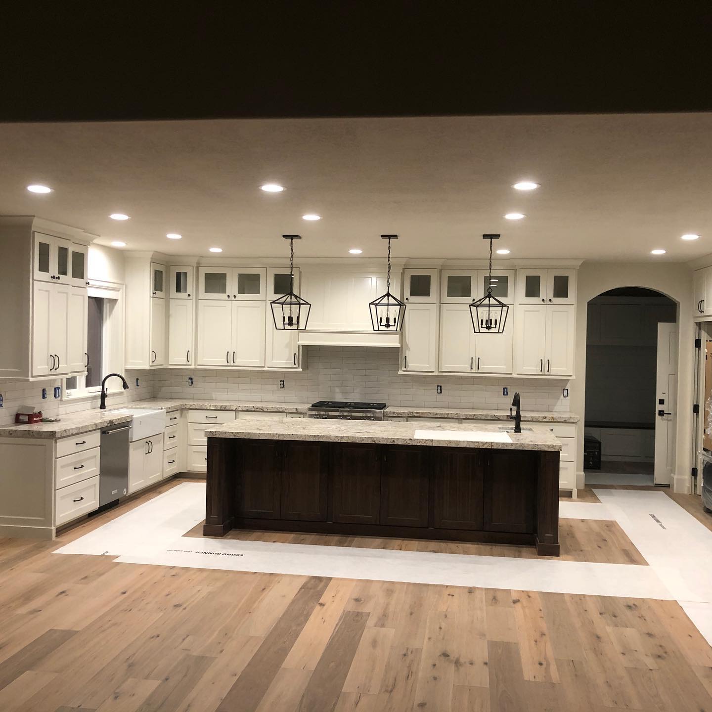 A kitchen with white cabinets and hardwood floors.